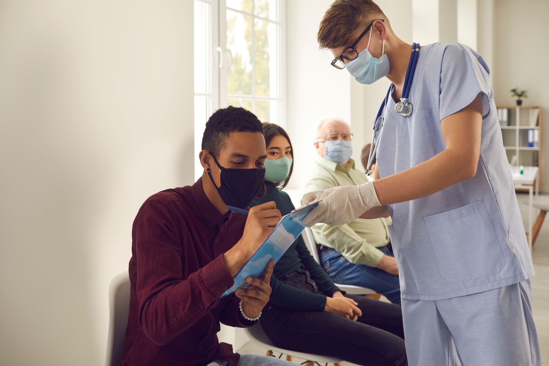 African-American man signs papers that doctor gives him before getting vaccine at the hospital