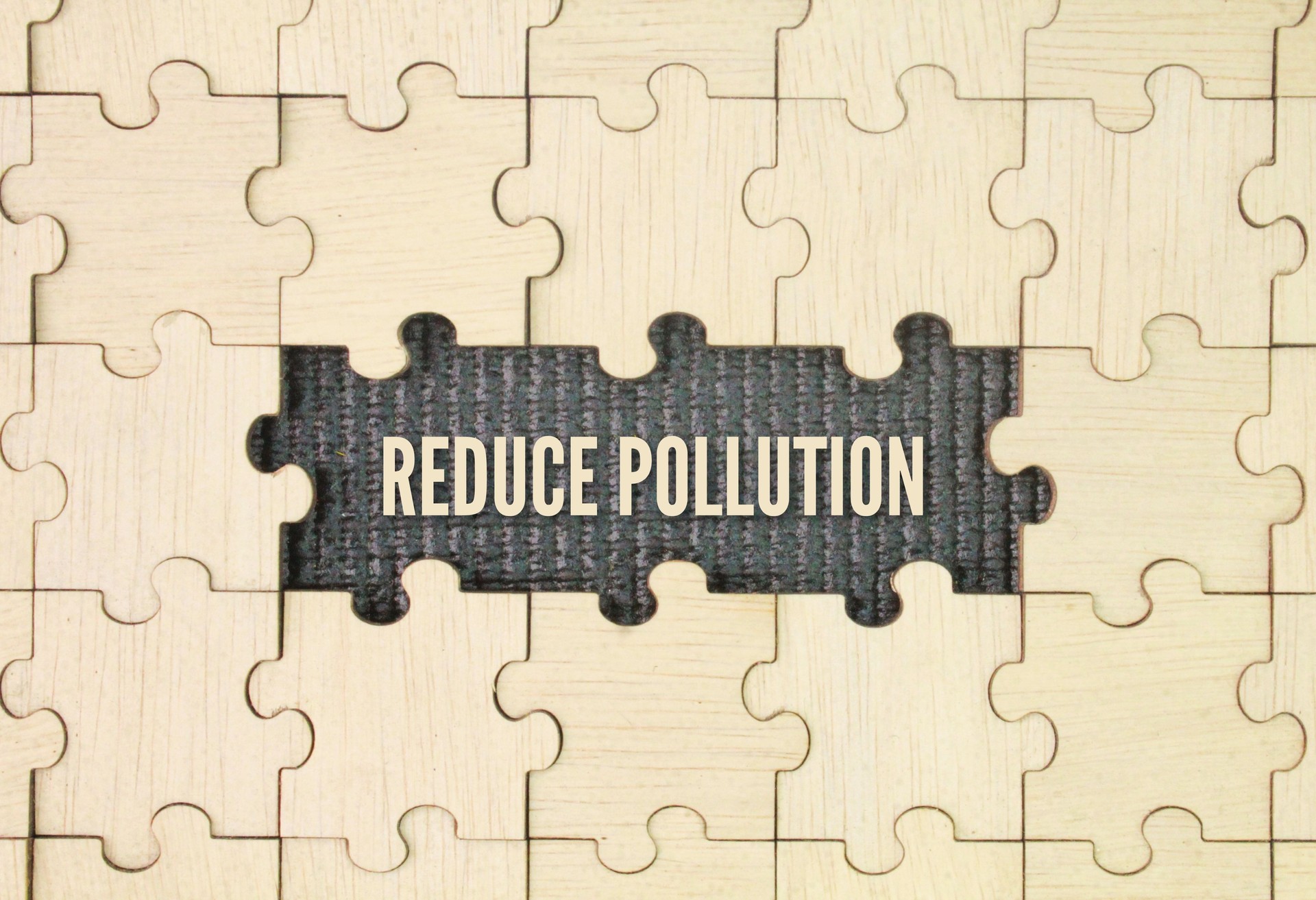 Wooden puzzle with the word reduce pollution. taking actions to decrease the amount of harmful substances released into the environment.