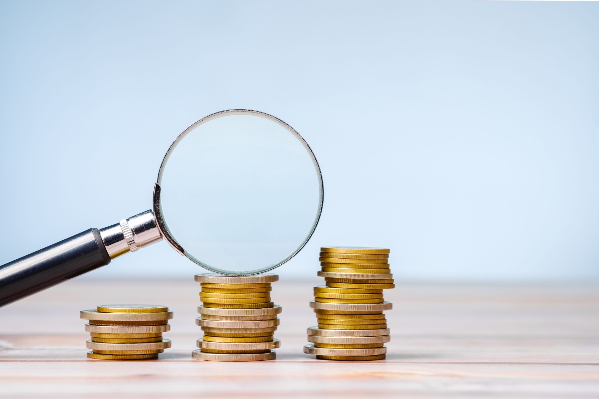 Magnifying glass on a few stacks of money coins