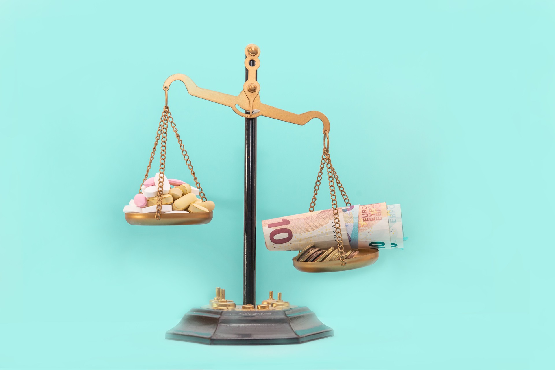 Scales with a stack of different pills and money euro banknotes and coins. Concept of healthcare costs, rising prices of medicines and nutritional supplements. Financial crisis in medicine