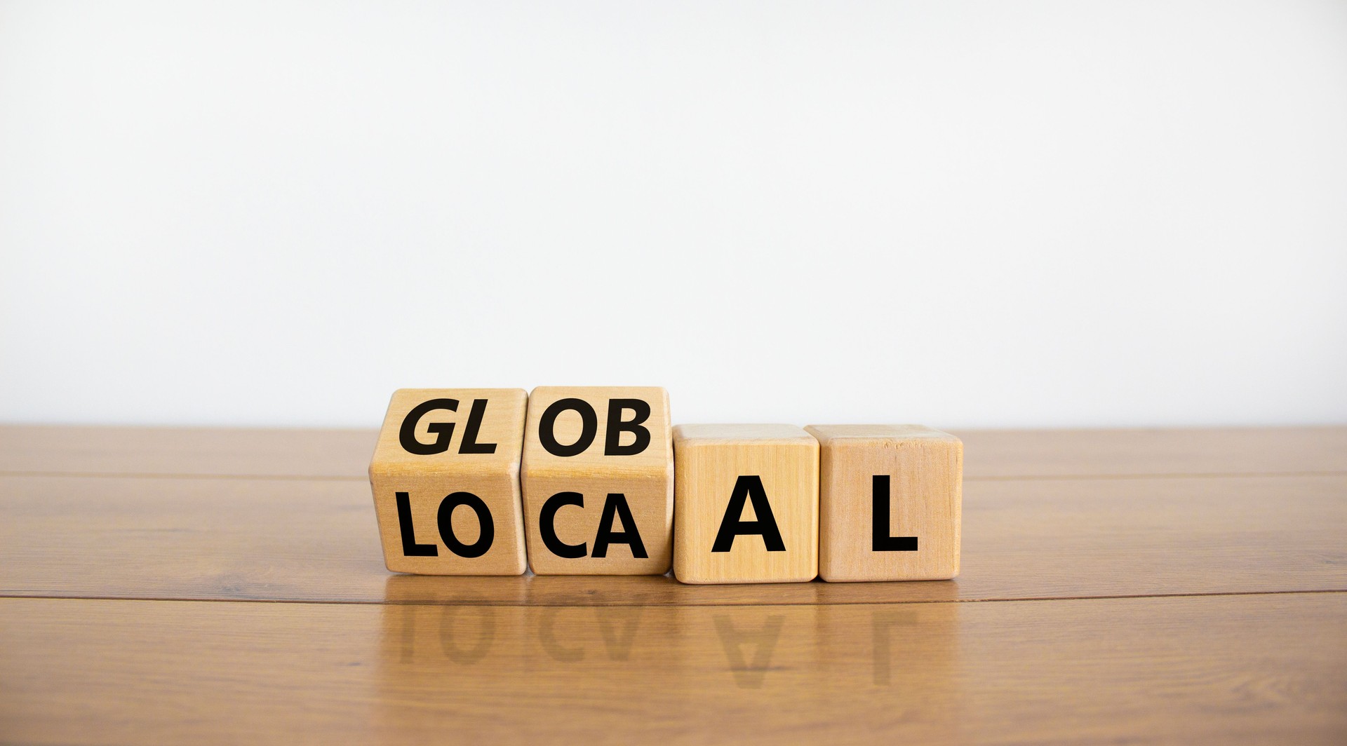 Local or global symbol. Turned wooden cubes and changed the word 'local' to 'global'. Beautiful wooden table, white background. Business and local or global concept. Copy space.