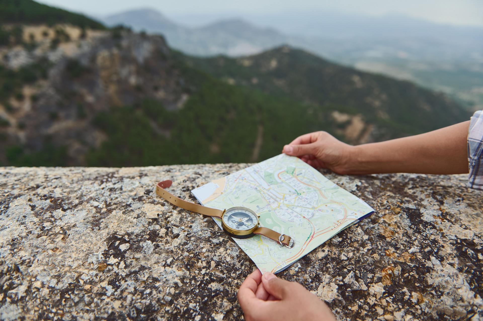 Traveler navigates with map and compass on a mountainous trail with scenic view