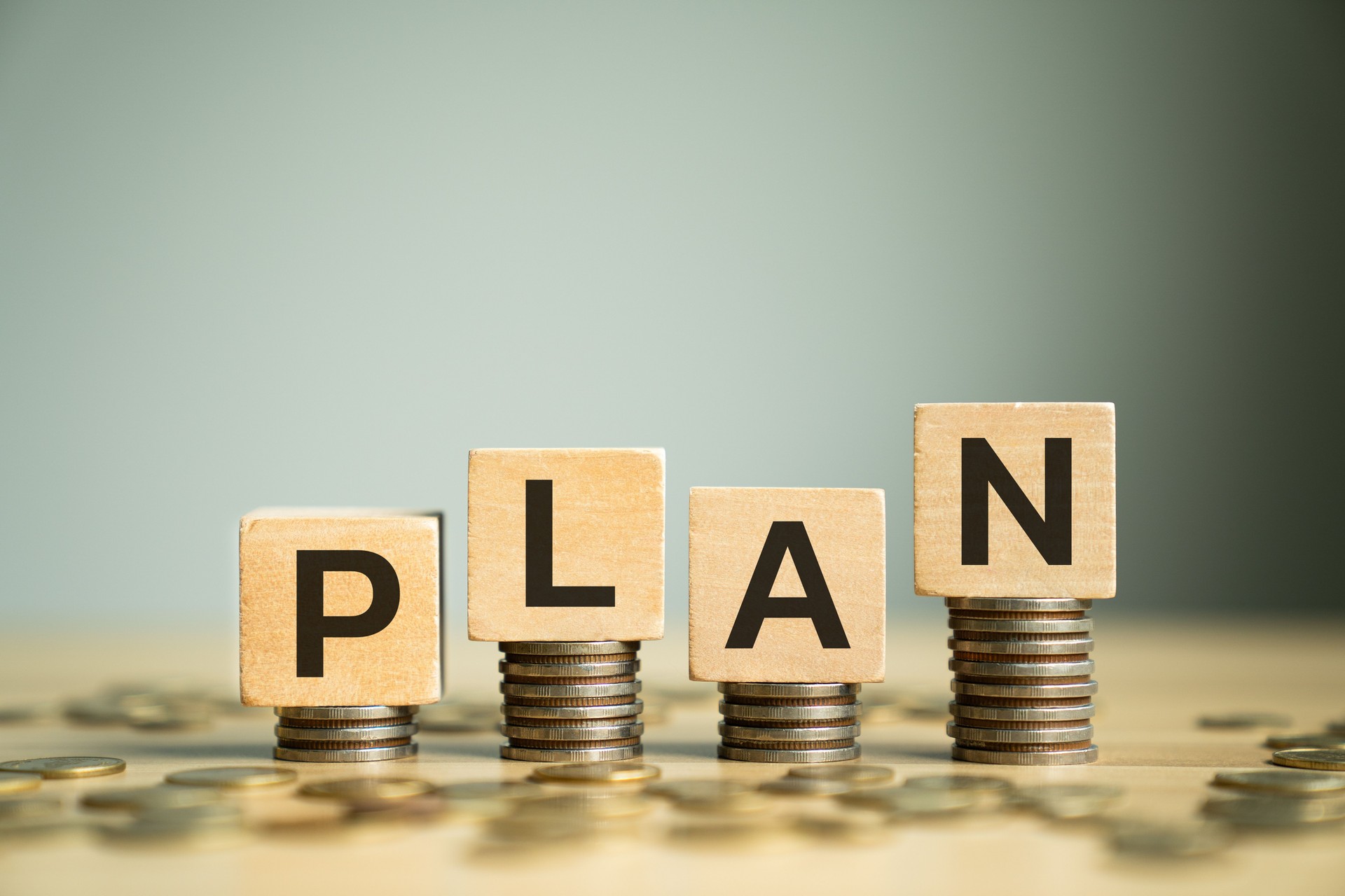 Wooden Block Letters Spelling PLAN Placed on Stacked Coins, Symbolizing Strategic Planning for Financial Growth, Budgeting, and Money Management in Personal and Business Finances
