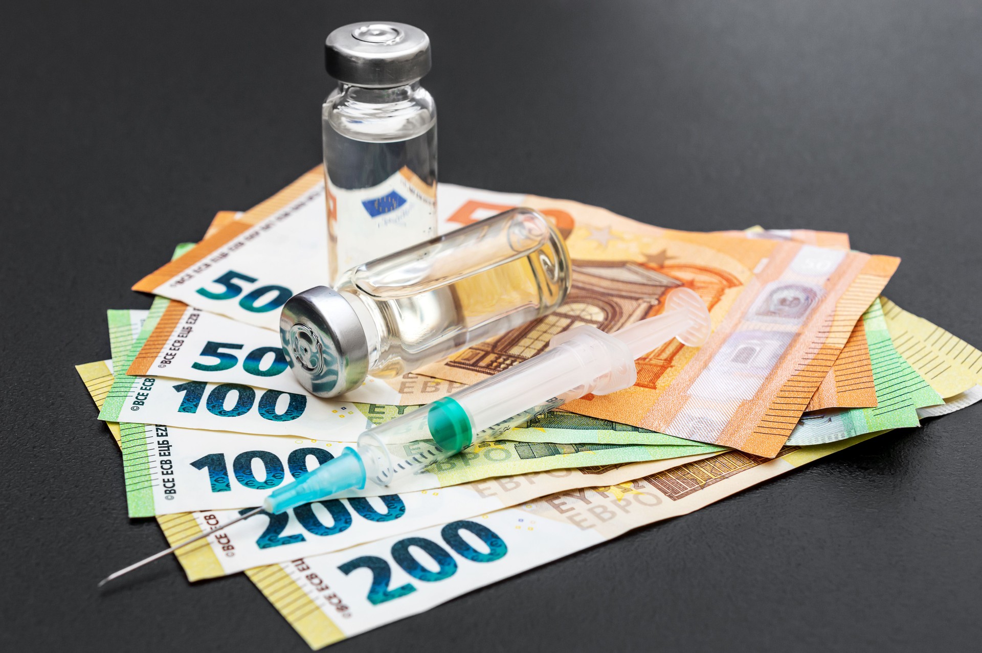 Vaccine vials with syringe and euro bills.
